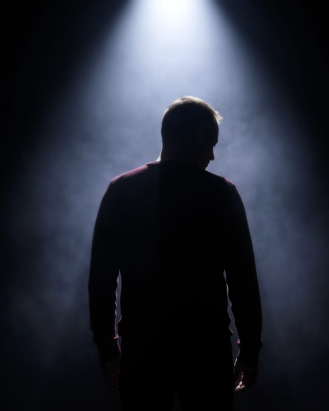 Psynuxx in silhouette beneath a spotlight
